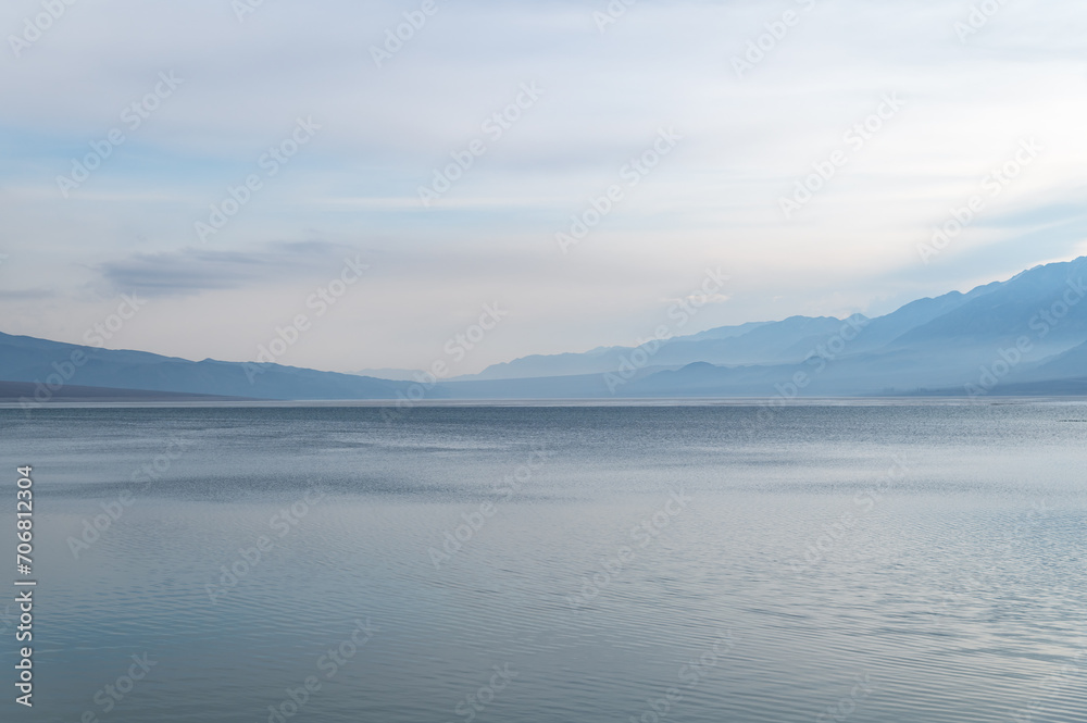 Silhouettes of misty mountains and lake. Beautiful mountain landscape. Orto-Tokoy reservoir in Kyrgyzstan in winter.