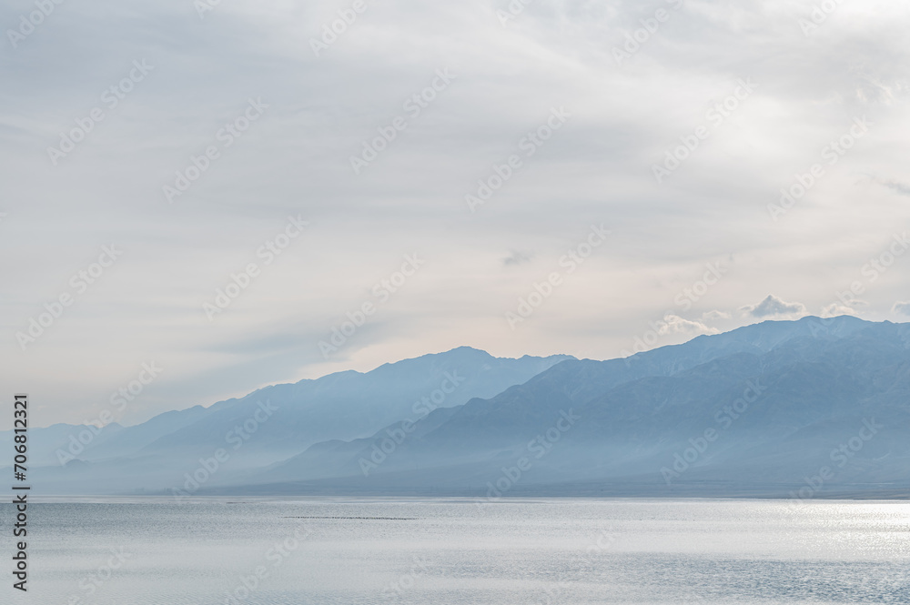 Obraz premium Bluish silhouettes of misty mountains and lake. Orto-Tokoy reservoir in Kyrgyzstan in winter.