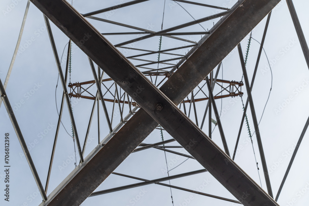 High-voltage power line support close-up. Metal pattern. View from below. The beauty of metal structures.