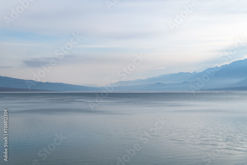 Silhouettes of misty mountains and lake. Beautiful mountain landscape. Orto-Tokoy reservoir in Kyrgyzstan in winter.