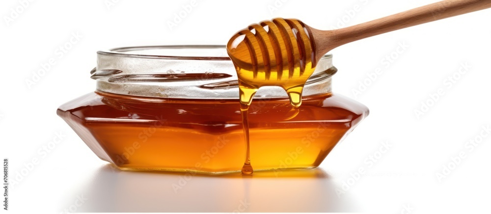 Honey in a jar with a honey dipper, isolated on a white background Honey in a jar with a honey dipper, isolated on a white background