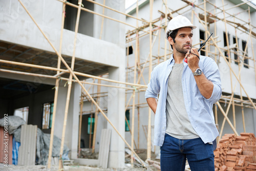 worker or architect using walkie talkie and talking to someone at construction site © offsuperphoto