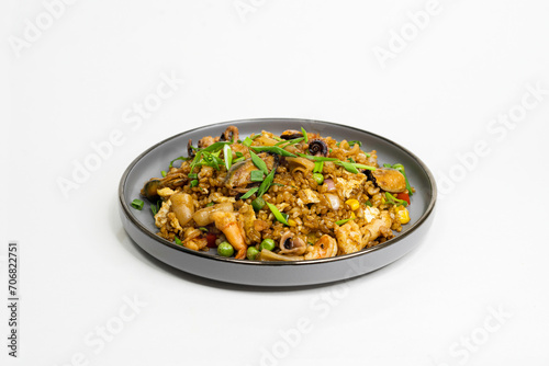fried noodles with vegetables and meat in a flat plate on a white background, side view