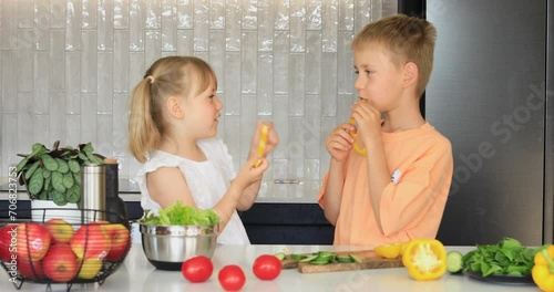 Funny brother and sister have fun eating sweet peppers and having fun. 