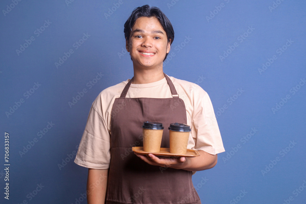 Portrait of waiter barista guy wear brown apron holding two paper cup of coffee on wooden tray with happy expression Portrait of waiter barista guy wear brown apron holding two paper cup of coffee on wooden tray with happy expression