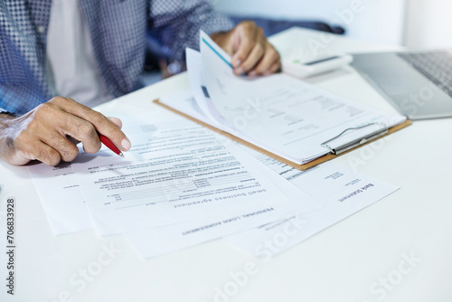 Asian man work at home holding pen check balance in bank statement, check important business documents before start new business SME as business owner, Close-up view