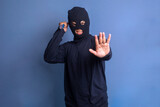 Furious burglar in black mask holding knife and raise hand showing stop gesture 