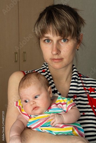 young blonde mother holding her little baby daughter in her hands