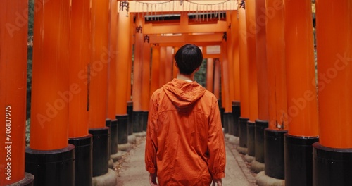 Tableau sur toile Man, outdoor and walk by shinto torii gate, back and culture for thinking, ideas and nature in forest