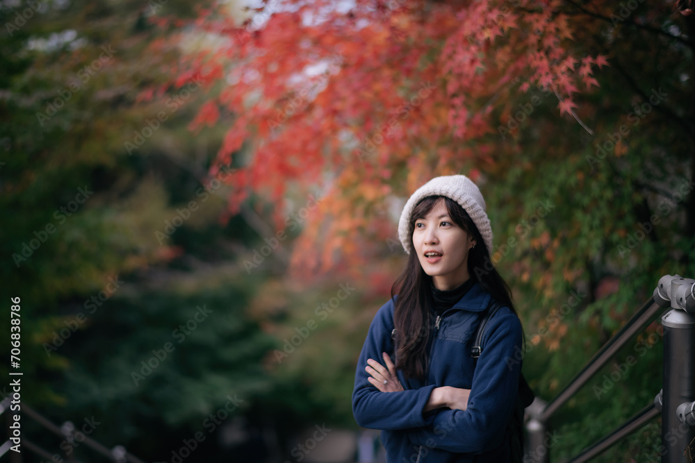 Asian woman in casual dress enjoys Japan's autumn in Kyoto. A cheerful holiday portrait capturing friends, smiles, and colorful foliage by the lake.