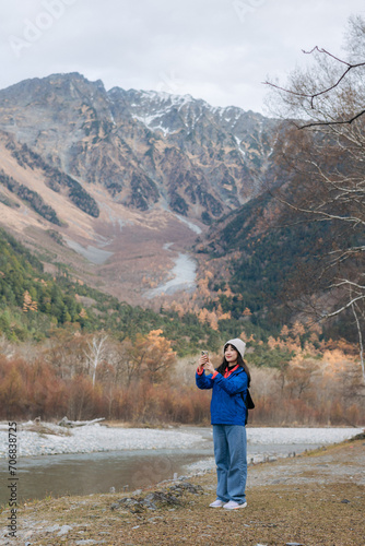 Achievement and happiness, Asian woman in a blue jacket explores nature's beauty. A stylish traveler in Japan, standing by a lake, reflecting on a journey of excitement.