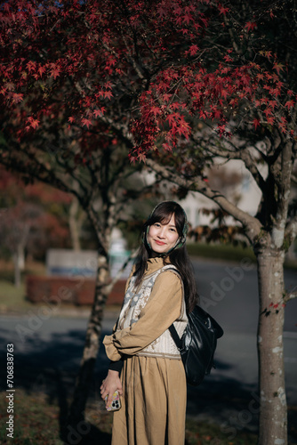 Asian woman in Kyoto's fall, wearing a casual dress, enjoys the beauty of nature, capturing cheerful smiles amid vibrant foliage and the scenic allure of Japan. © Jirawatfoto