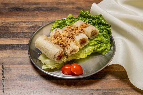 Deep fried Shrimp Spring Rolls with lettuce leaf and tomato served in dish isolated on wooden table top view of hong kong fast food