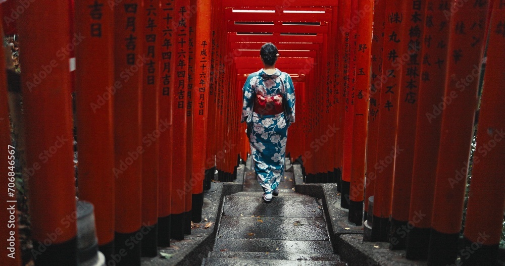Fototapeta premium Woman, shinto religion and walk by gates in japan, spiritual path and indigenous culture in kimono. Person, traditional clothes or worship in peace, respect or beauty by Fushimi Inari Taisha in kyoto