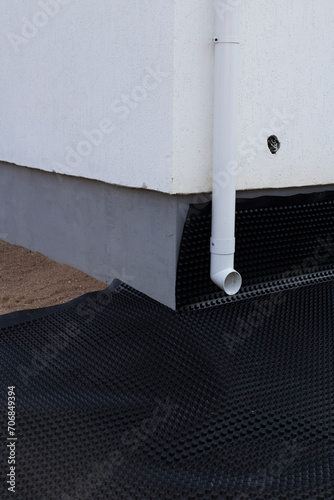 Black waterproofing membrane around the foundation of the house. Construction of the blind area of the house. Reliable protection of the foundation from moisture.