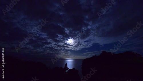 검푸른 밤하늘에 초승달 앞을 지나는 구름과 밤바다에 비친 달무리 미속 촬영 영상  photo