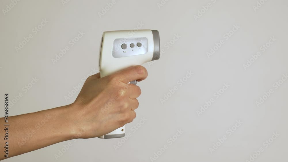 Hand using infrared thermometer, white background