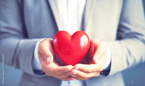 Businessman hands holding a red heart in the concept of love and health © Kanokmai
