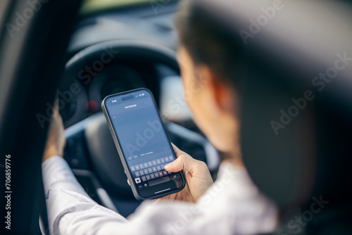 Selective focus on hand typing a message while a woman driving a car. photo