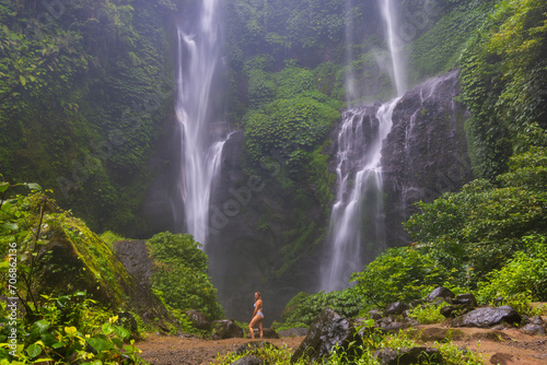 A young woman in swimming suit in front of Sekumpul Waterfall in Bali Island, Indonesia