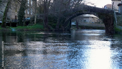 Water shimmers as it flows and light reflects bright off it fronting roman bridge photo