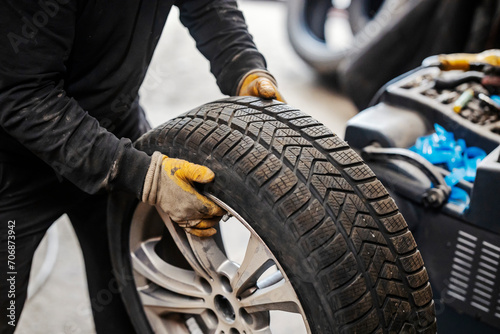 Close up of mechanic's hands holding car wheel at vulcanizing workshop.