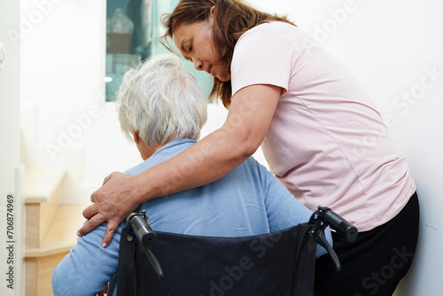 Asian senior woman on wheelchair with caregiver help support walking down the stairs prevent accident, slip and fall at home. photo