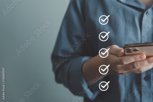 Businessman hand using smartphone and tick correct check mark for accept or approve request action. Checklist, Survey, Assessment, Term of service agreements and Personal Data Protection Act concept.