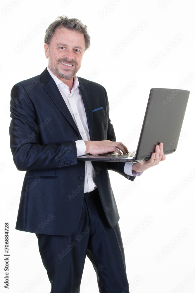 Smiling handsome professional man fifties middle age working over laptop while standing on white background