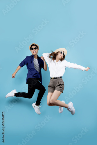 Asian couple jumping for joy isolated on blue background.