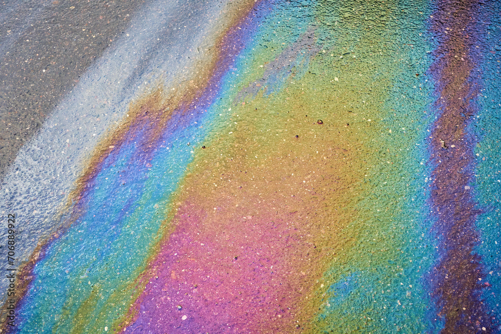 Obraz premium Oil stain on the asphalt, rainbow-shaped colored gasoline stains on an asphalt road as a texture or background