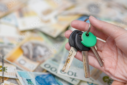 Kupować mieszkanie, klucze w dłoni na tle rozmytych pieniedzy