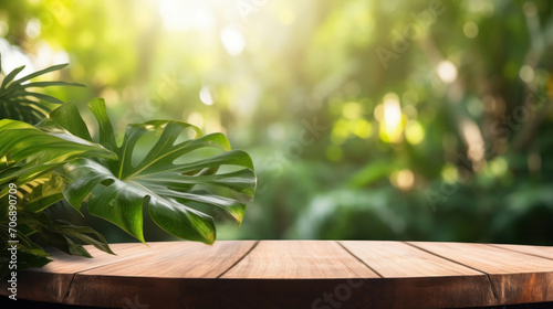 Lush green Monstera leaves arranged on a round wooden table  with the sunlit forest as a tranquil backdrop.