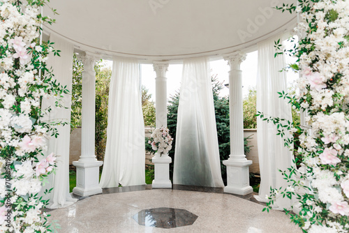 Luxurious white wedding arch decorated with flowers photo