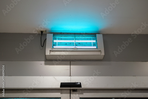An insect or mosquito elimination device during turn-on the UV lighting which is installed on ceiling wall, the household electric equipment object. Close-up. photo