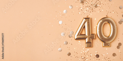 40 years celebration. Greeting banner. Gold candles in the form of number forty on peach background with confetti. photo