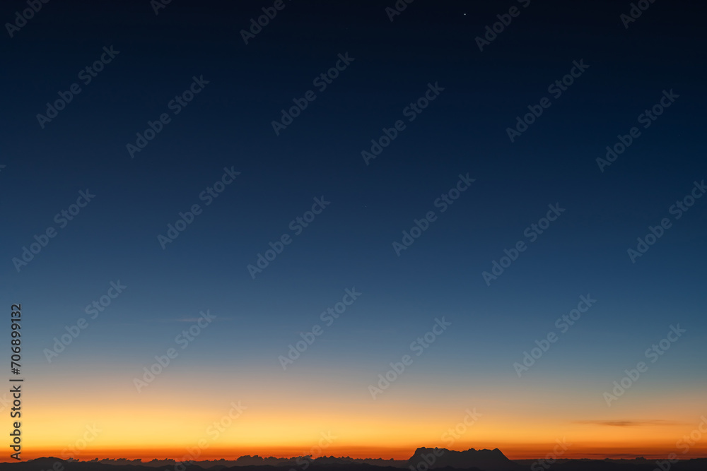 Predawn clear sky with orange horizon and blue atmosphere. Smooth orange blue gradient of dawn sky. Heaven at early morning with copy space. Sunset, sunrise backdrop.