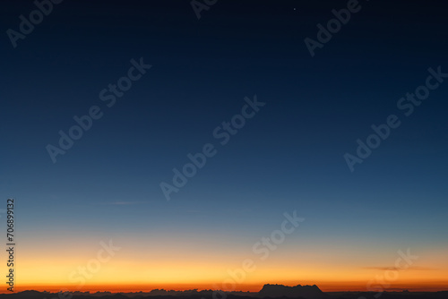 Predawn clear sky with orange horizon and blue atmosphere. Smooth orange blue gradient of dawn sky. Heaven at early morning with copy space. Sunset, sunrise backdrop.
