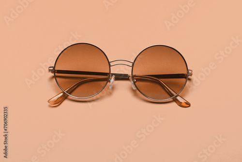 Beautiful trendly sunglasses on a pink background. New trending PANTONE Peach Fuzz colour of 2024 year