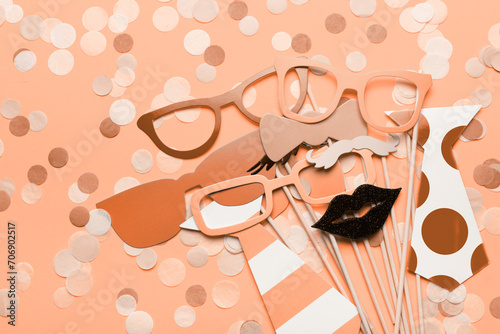 Photo booth props glasses, mustache, lips on a pink background flat lay. New trending PANTONE Peach Fuzz colour of 2024 year (ID: 706902517)