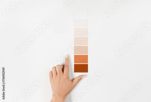 Hand holding Color samples palette design catalog. New trending PANTONE Peach Fuzz colour of 2024 year (ID: 706902949)