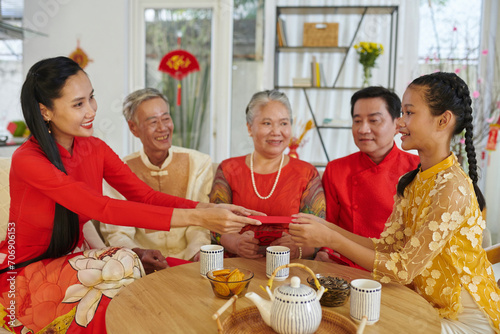 Smiling mother giving lucky money envelope to her teenage daughter at Tet celebration photo