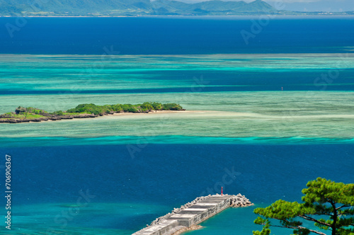 Amazing view of gradient blue sea, green islet, long pier. Iriomote Island.