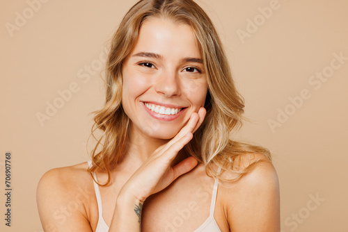 Close up young nice lady woman with slim body perfect skin wears nude top bra lingerie stand put hand touch face look camera isolated on plain pastel light beige background Lifestyle diet fit concept photo