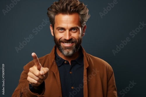handsome smiling bearded man looking into the frame and pointing his finger at something in front of him attracting attention