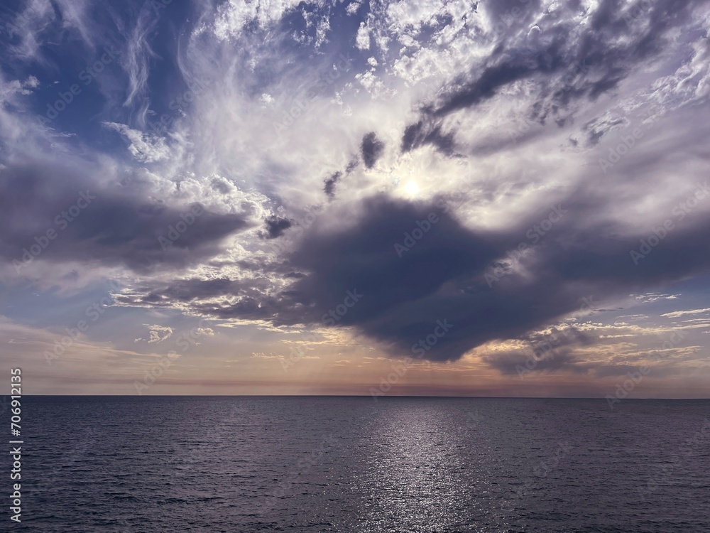 Fototapeta premium Sunset sky clouds over sea glittering water at evening.