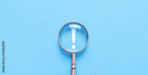 magnifying glass shows an icon exclamation mark on a blue background. points attention. concept of signal alert, caution, or idea. information important in business and security