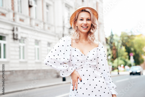 Young beautiful smiling blond woman in trendy summer white dress. Sexy carefree woman posing in the street  at sunset. Positive model outdoors at sunny day. Cheerful and happy. In hat © halayalex