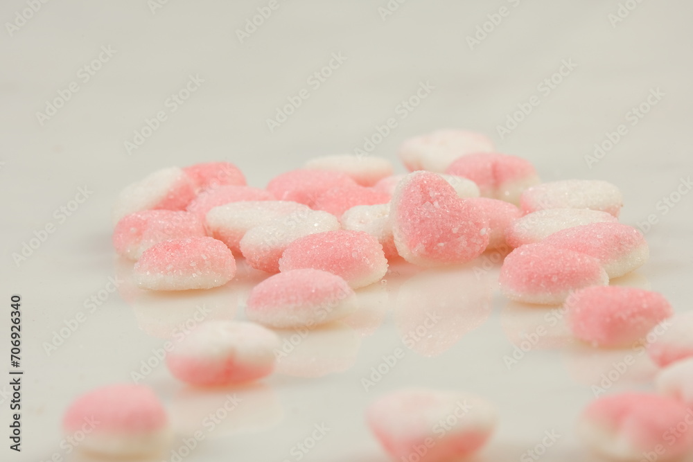 Heart-shaped pink chewy candies with sugar sprinkles on white background Heart-shaped pink chewy candies with sugar sprinkles on white background