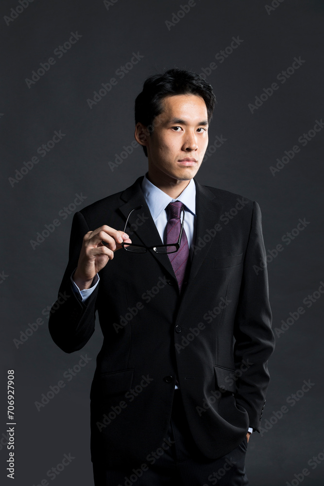Stylish Chinese business man. In front of dark background Stylish Chinese business man. In front of dark background